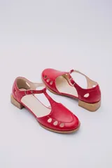 Sandalias rojas de cuero con talón cubierto, pulsera con hebilla al tobillo, puntera cerrada con aberturas circulares y taco bajo de madera.