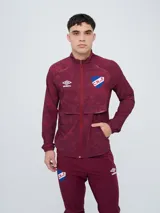 Campera deportiva Umbro del Club Nacional de Football, modelo Grok, en color bordó con diseño estampado sutil. Cuenta con cierre frontal completo, cuello alto y bolsillos laterales.