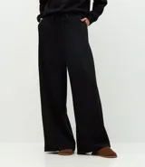 Pantalón de corte recto con cintura estructurada y lazo ajustable. Presenta un diseño básico y versátil con aberturas laterales en el ruedo.