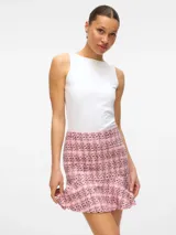 Pollera corta de tiro alto confeccionada en tejido de tweed con diseño a cuadros. Presenta un corte ajustado en la parte superior con un detalle de volado en el ruedo.