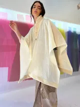 Ruana color crudo tejida en lana merino con cuello plisado a mano y terminaciones en fieltro de lana.