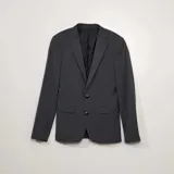 Chaqueta de traje de corte clásico en color gris oscuro, con cierre frontal de dos botones, solapas de muesca y bolsillos laterales con solapa.