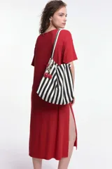 Vestido midi color beige, de corte oversized, con cuello redondo, manga corta y tajos laterales. Presenta un parche decorativo en la manga.