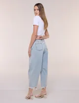Jean de tiro medio y calce holgado con silueta curva y corte baggy, color azul claro. Cuenta con costuras diagonales estructuradas en el frente, cinco bolsillos, presillas en la cintura y cierre frontal con botón metálico. Presenta un ruedo al tobillo con acabado desflecado e irregular.