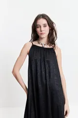 Vestido largo de silueta amplia y fluida, con breteles finos y escote redondeado. Presenta un diseño estampado con motivos geométricos en tonos bordó, beige y gris.