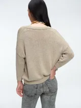 Sweater de punto con brillo, de corte relajado y escote en V. Presenta hombros caídos y mangas largas con puños acanalados.