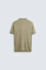 Polo de punto negro, manga corta, con cuello solapa y cierre frontal de tres botones. Presenta un calce regular y acabados en rib en mangas y ruedo.