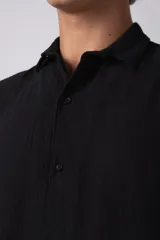 Camisa de hombre de manga corta color beige claro, confeccionada en lino. Tiene cuello clásico, cierre frontal con botones y corte recto.