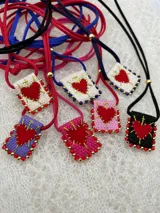 Collar con dije rectangular bordado con un corazón rojo y detalles de mostacillas de colores.