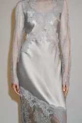 Vestido largo de satén y encaje color gris, con cuello redondo, manga larga y cierre en la espalda con abertura y botón.