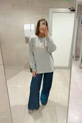 Buzo gris de calce oversize con cuello redondo y mangas largas. Presenta el logo de la marca bordado en el frente y un parche con la bandera de Uruguay en la manga izquierda.