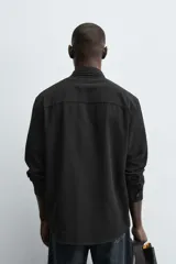 Camisa de corte regular fit confeccionada en tejido de algodón con textura de cuadrillé. Presenta cuello solapa, manga larga con puños abotonados y cierre frontal mediante botonadura.