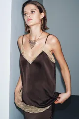 Top de tejido satinado color marrón oscuro, con escote recto y tirantes finos ajustables. Presenta aplicación de encaje color beige a contraste en el escote y el bajo.