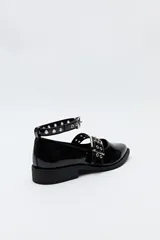 Zuecos de charol color borgoña con punta fina, correa al tobillo y doble tira sobre el empeine con hebillas metálicas plateadas.