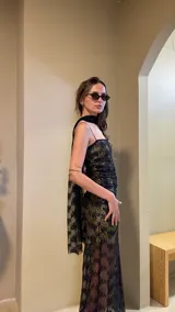 Vestido largo negro con estampado dorado, de breteles finos y corte ajustado.