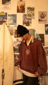 Buzo de estilo vintage con medio cierre frontal, confeccionado en tela con efecto lavado color bordó. Presenta cuello alto con detalle de rayas, mangas largas holgadas y logo bordado en el pecho.