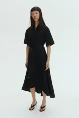 Vestido midi negro con cuello camisero, mangas cortas y botones ocultos. Incluye un cinturón fino con hebilla metálica dorada en la cintura y falda evasé de corte midi.