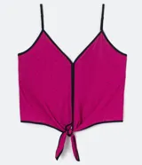 Musculosa cropped fucsia con estampa de lunares negros, escote en V, tiras finas regulables y nudo frontal con bordes negros contrastantes.