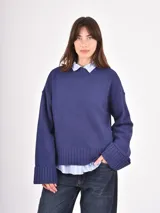 Buzo de tejido de punto en color azul, con cuello redondo, mangas largas con puños anchos acanalados y ruedo también acanalado. Presenta un diseño holgado y cómodo.