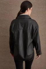 Camisa de cuero color tostado con cuello de corderito sintético, cierre frontal con botones a presión metálicos y bolsillos frontales con solapa.