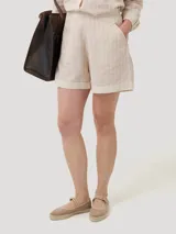 Short de tiro alto confeccionado en mezcla de lino y algodón orgánico, con diseño de rayas verticales en tonos beige y blanco. Presenta bolsillos laterales y cierre invisible.