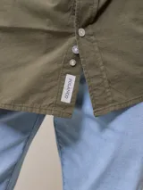 Camisa de manga larga para hombre, confeccionada en algodón con efecto peach (textura suave). Presenta un estampado de cuadros vichy en tonos azul marino y blanco, cuello con botones y un bolsillo de parche en el pecho izquierdo.