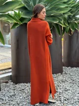 Vestido largo de punto en color verde oliva, con diseño de paneles en dos tonos de verde, mangas largas con textura perforada y tajos laterales en el ruedo.