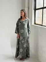 Vestido largo color verde militar con estampado floral, cuello drapeado y mangas largas de corte holgado.