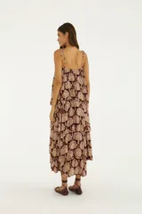 Vestido largo bordó con estampado paisley, escote recto y tirantes finos. Presenta un diseño de múltiples volantes superpuestos con hilos metalizados que aportan movimiento y textura.
