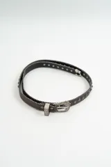 Cinturón de cuero marrón con bordes decorados con pequeñas tachas metálicas plateadas. Incluye hebilla de estilo western grabada y pasador metálico a juego.