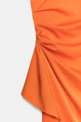 Vestido midi asimétrico de satén color naranja, con una sola manga corta abullonada, diseño drapeado en el lateral y falda cruzada.