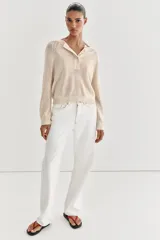 Jersey de punto color beige, con cuello redondo y cierre frontal parcial de botones, manga larga y acabados en rib.