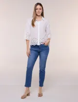 Camisa de calce holgado color blanco, confeccionada en tejido liviano de algodón, con cuello camisero clásico, mangas tres cuartos y terminación en puños y ruedo con diseño de bordado broderie calado y festoneado.