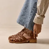 Sandalias franciscanas de cuero marrón oscuro, con diseño de tiras entrelazadas, tira en T con hebilla metálica ajustable y suela con plataforma.