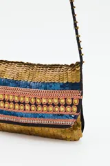 Cartera tipo sobre con diseño de lentejuelas en franjas horizontales de colores dorado, azul y rosado. Incluye una correa larga de cordón negro con detalles de cuentas doradas y borlas en los extremos.