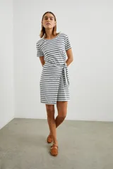 Vestido corto a rayas horizontales azul marino y blanco, con cuello redondo, mangas cortas y falda cruzada con lazo lateral.