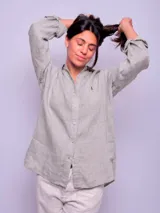 Camisa de lino color gris melange, de manga larga con puños arremangables y cierre frontal con botones a tono. Cuenta con cuello camisero clásico y pequeño detalle bordado en el pecho.