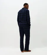 Pijama largo para hombre confeccionado en franela de algodón con estampado a cuadros en tonos azul marino y negro. Consta de una camisa de manga larga con cuello solapa, cierre frontal de botones y un pantalón largo de corte recto y cómodo.