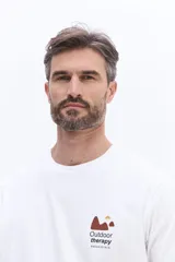 Remera de manga corta color gris oscuro, con cuello redondo y estampa pequeña en el pecho con diseño de montañas y texto.