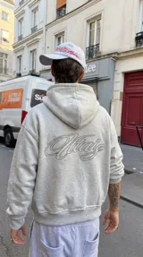 Hoodie gris melange con capucha, cierre frontal y gran bordado en relieve en la espalda.