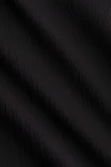 Top negro sin mangas de punto elástico texturizado, con escote bote y frunces en los laterales que crean un leve efecto drapeado.