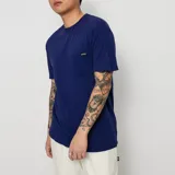 Remera azul de manga corta con bolsillo en el pecho y logo de la marca en la etiqueta.