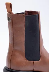 Bota marrón de símil cuero, con punta redondeada, pieza elastizada negra en los laterales y plataforma de 6cm.