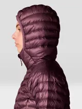 Campera puffer ultraligera de Mountain Hardwear, modelo Ghost Whisperer, en color bordó. Presenta diseño acolchado con costuras horizontales, cierre frontal completo, capucha integrada y bolsillos laterales con cierre. Incluye puños con ajuste elástico y aislamiento térmico de alta calidad.