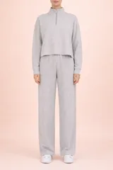 Conjunto de dos piezas en tejido de punto acanalado color gris. Incluye un buzo de corte cropped con cuello alto y cierre frontal, y un pantalón de corte recto con cintura elástica.