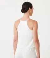 Blusa blanca de poliéster con escote en pico, tirantes finos ajustables y corte cruzado.