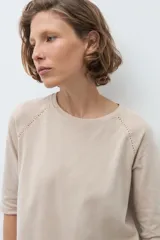 Remera de manga tres cuartos con diseño raglán y detalle de costura decorativa en los hombros. Presenta cuello redondo y un corte clásico.