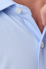 Camisa de vestir celeste rayada de manga larga, con cuello camisero, bolsillo ojal en el pecho y cierre frontal con botones.