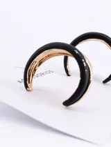 Set de caravanas tipo argolla con diseño bicolor, combinando una sección en color negro mate y otra en acabado dorado brillante.