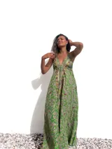 Vestido largo de estilo bohemio en color verde, con estampado paisley, escote en V profundo y breteles finos. Presenta detalles bordados con pedrería y espejos a lo largo del escote y el centro del frente, con una falda amplia y fluida.